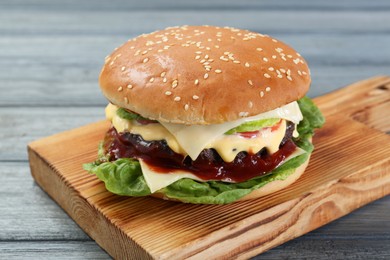Photo of Tasty homemade cheeseburger with lettuce on grey wooden table, closeup