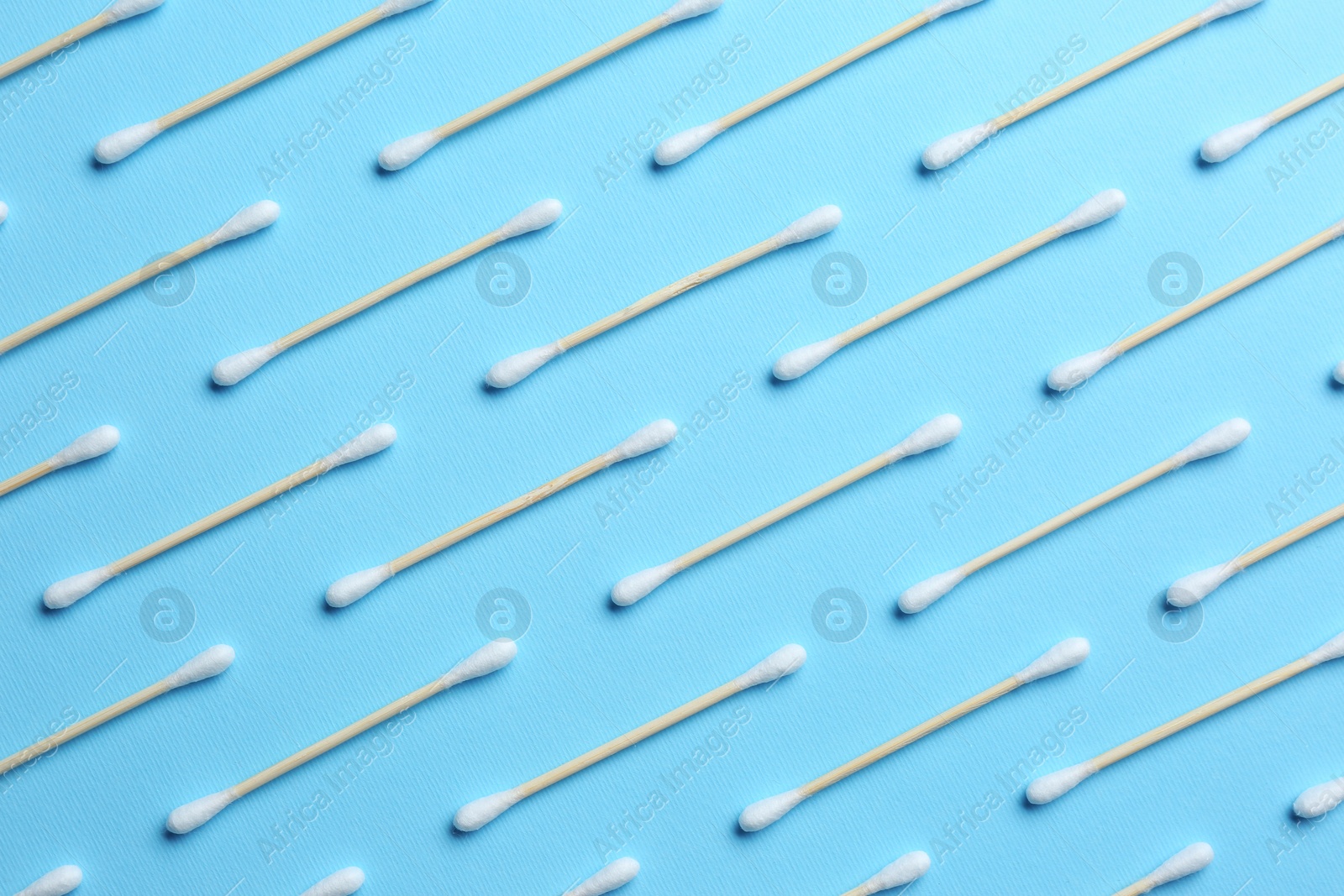 Photo of Many cotton buds on light blue background, flat lay