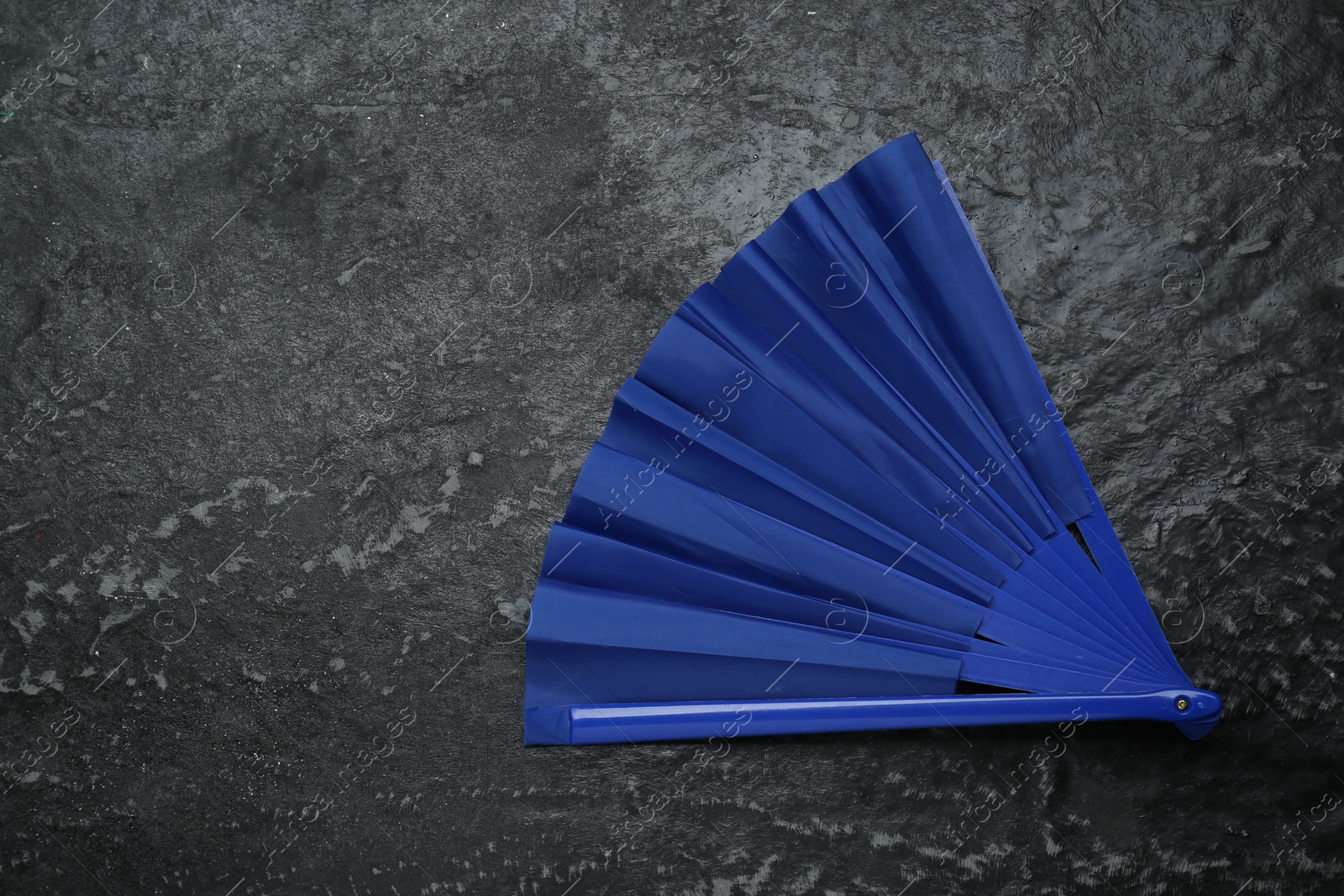 Photo of Bright blue hand fan on grey textured background, top view. Space for text