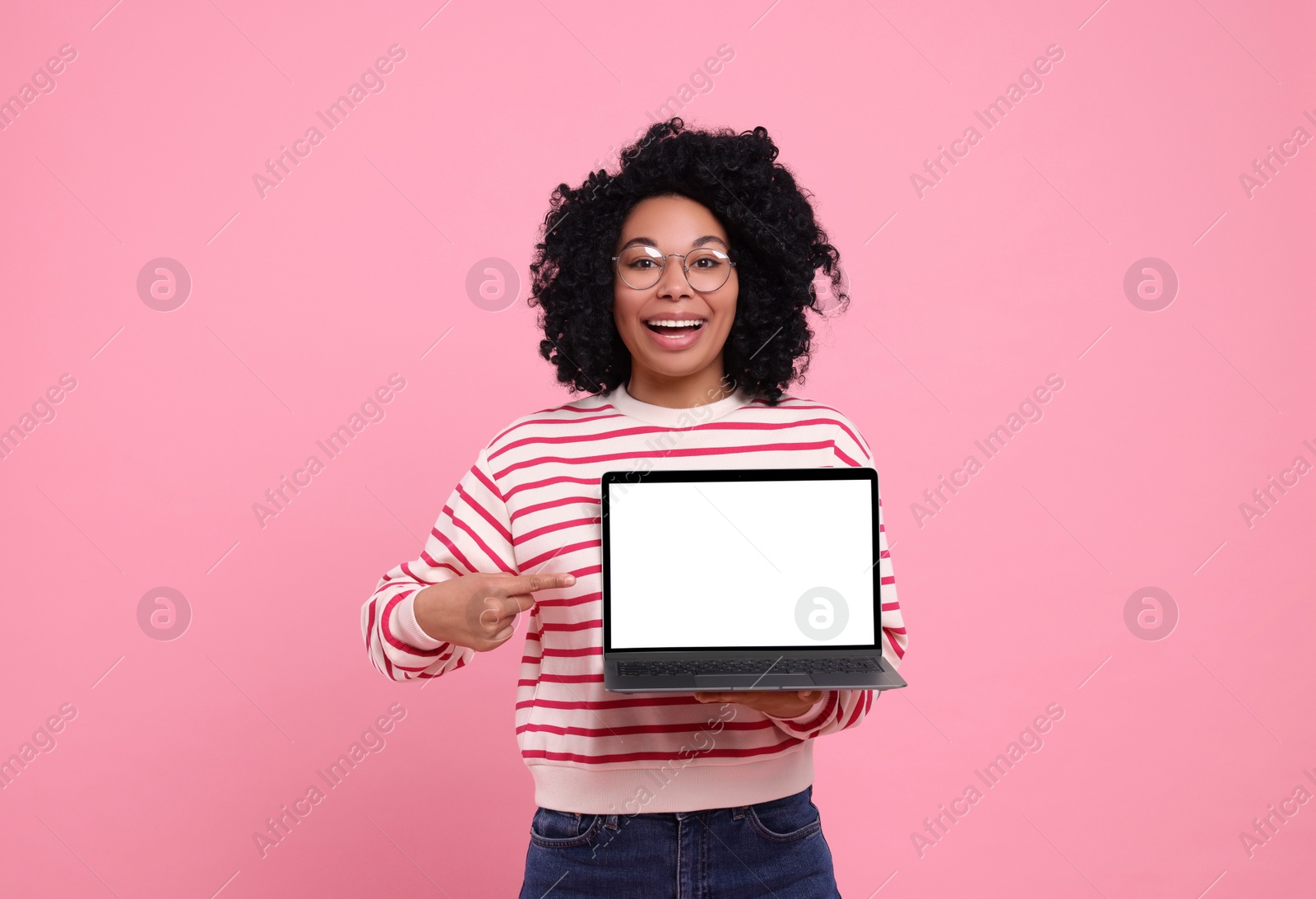 Photo of Happy young woman showing laptop on pink background
