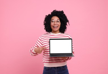 Happy young woman showing laptop on pink background