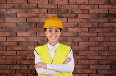 Female industrial engineer in uniform on brick wall background. Safety equipment