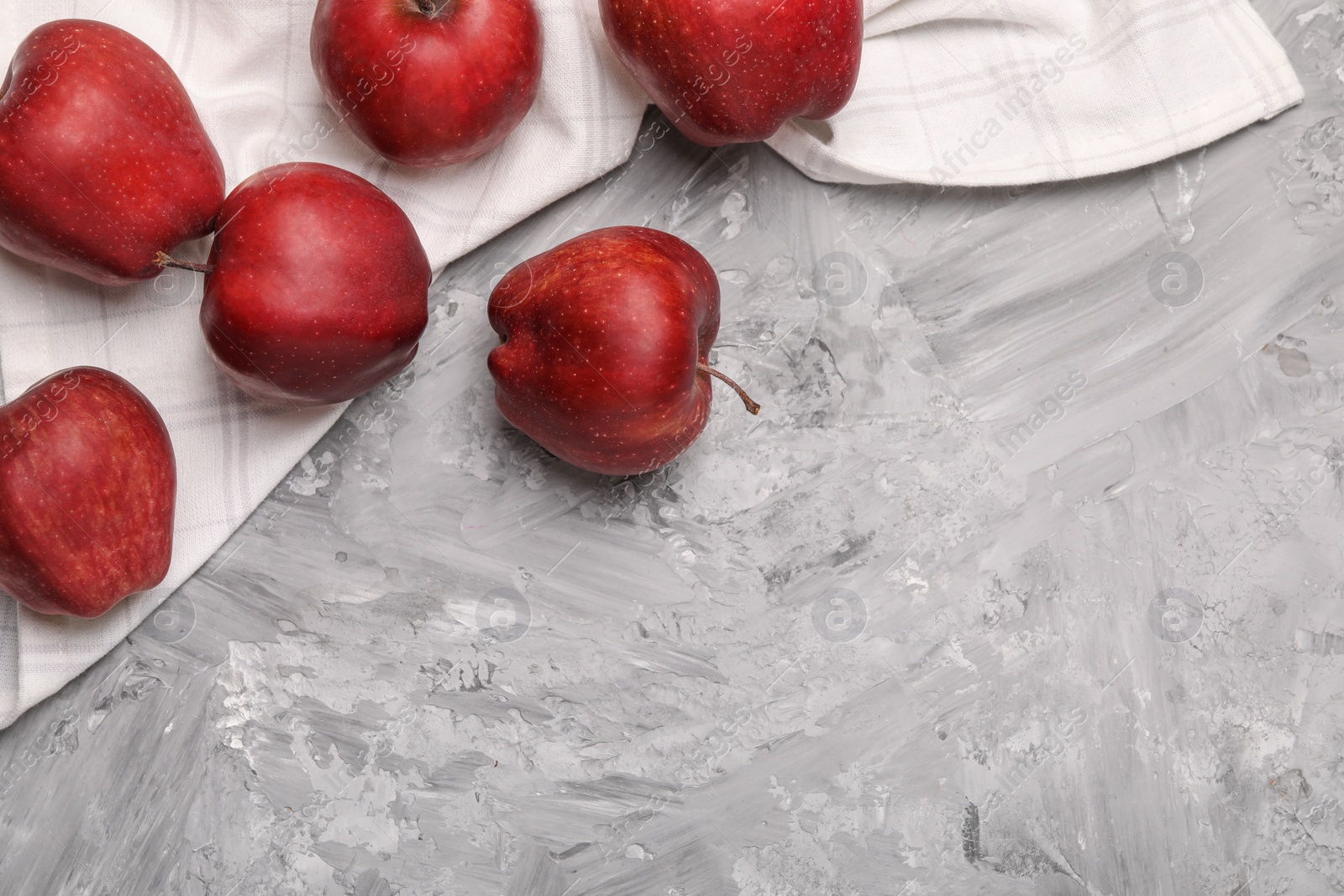 Photo of Fresh red apples on grey textured table, flat lay. Space for text