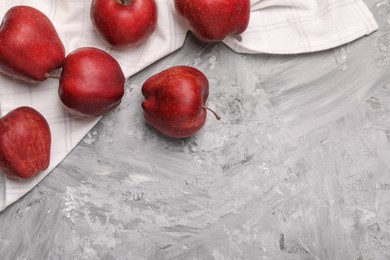 Fresh red apples on grey textured table, flat lay. Space for text