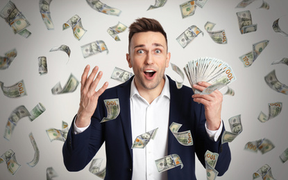 Image of Happy young man with dollars under money rain on light background