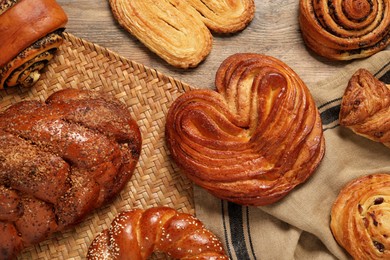 Different tasty freshly baked pastries on wooden table, flat lay