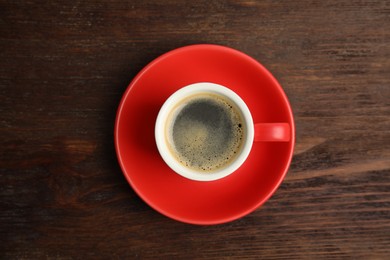 Cup of hot aromatic espresso on wooden table, top view