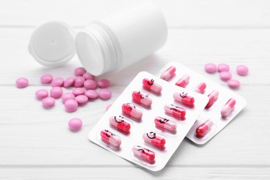 Photo of Blisters of antidepressants with different emoticons and medical jar on white wooden table