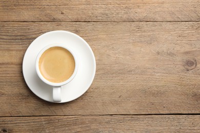 Photo of Aromatic coffee in cup on wooden table, top view. Space for text