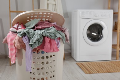 Photo of Laundry basket with baby clothes and shoes in bathroom