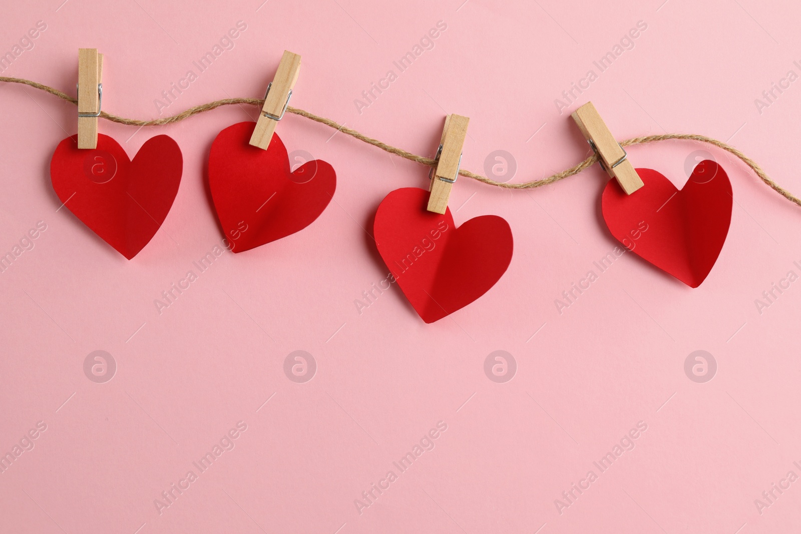 Photo of Red hearts, rope and clothespins on pink background, top view with space for text. St. Valentine's day