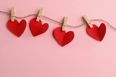 Red hearts, rope and clothespins on pink background, top view with space for text. St. Valentine's day