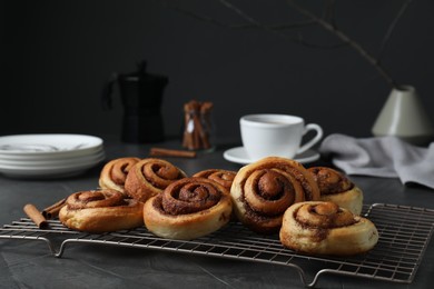 Tasty cinnamon rolls on black table, space for text