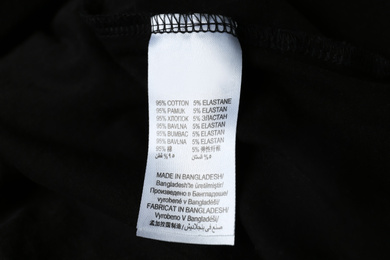 Photo of Clothing label with material content on black shirt, closeup view