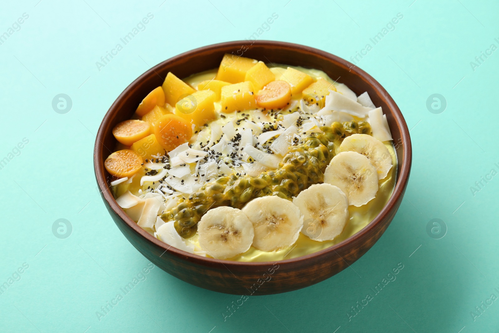 Photo of Tasty smoothie bowl with fresh fruits on turquoise table