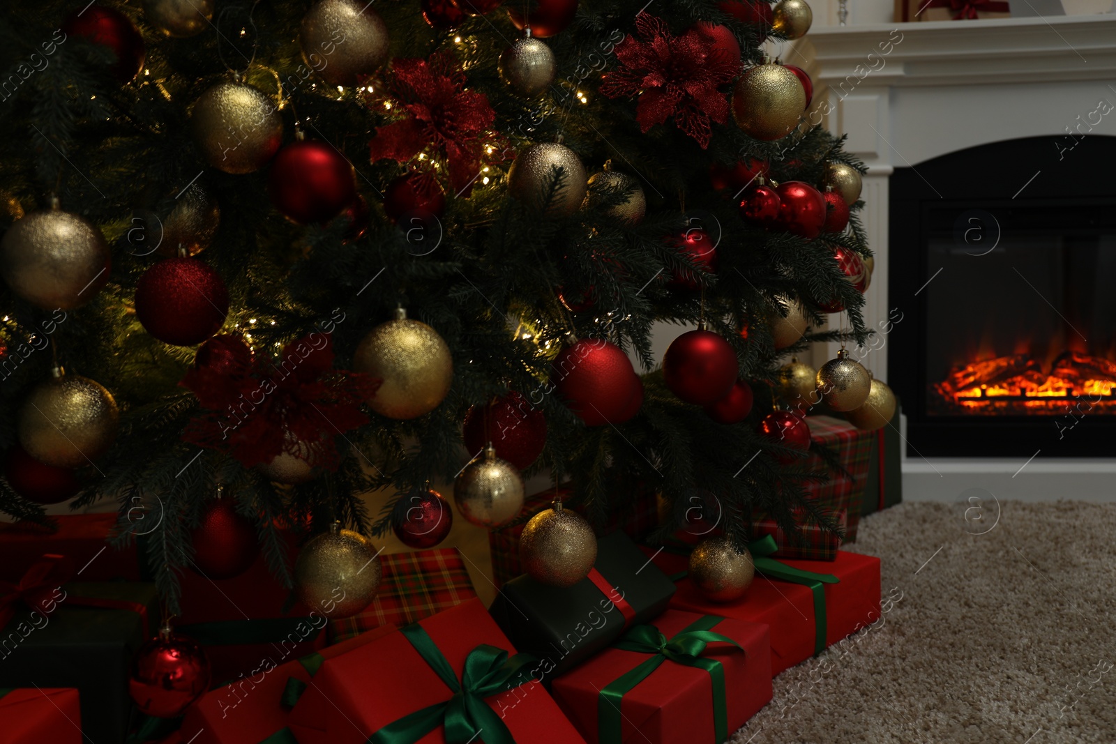 Photo of Gift boxes near Christmas tree in room with fireplace