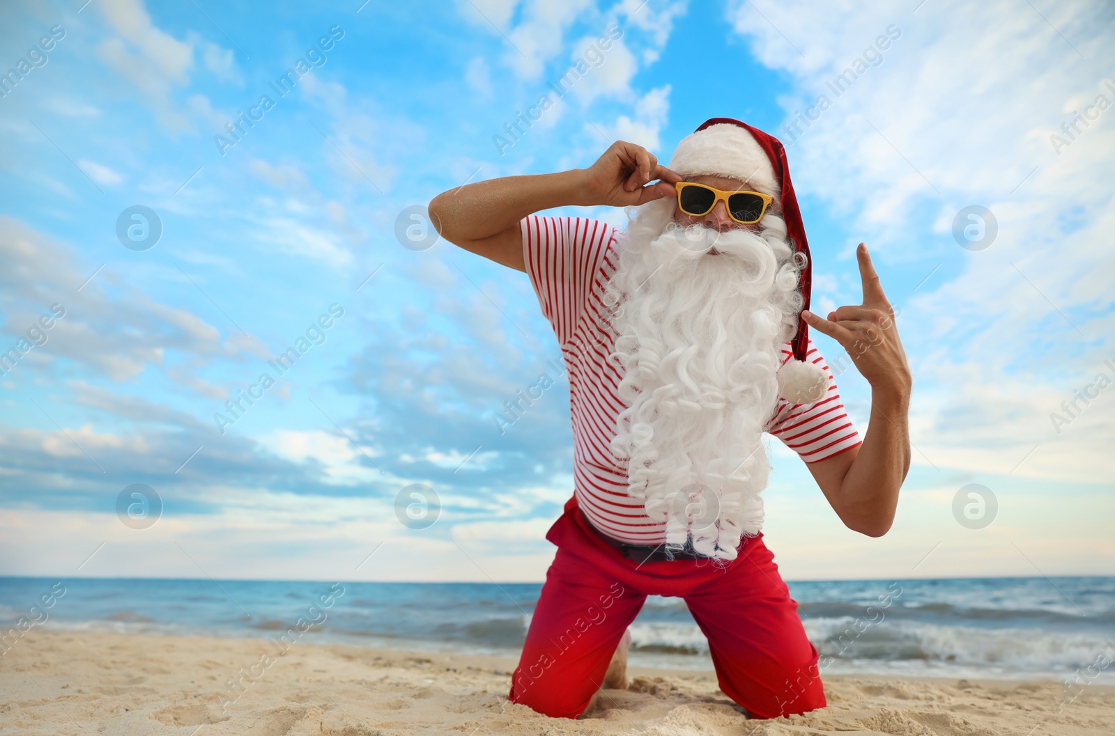 Photo of Santa Claus having fun on beach, space for text. Christmas vacation