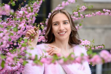 Photo of Beautiful young woman near blossoming sakura tree on spring day