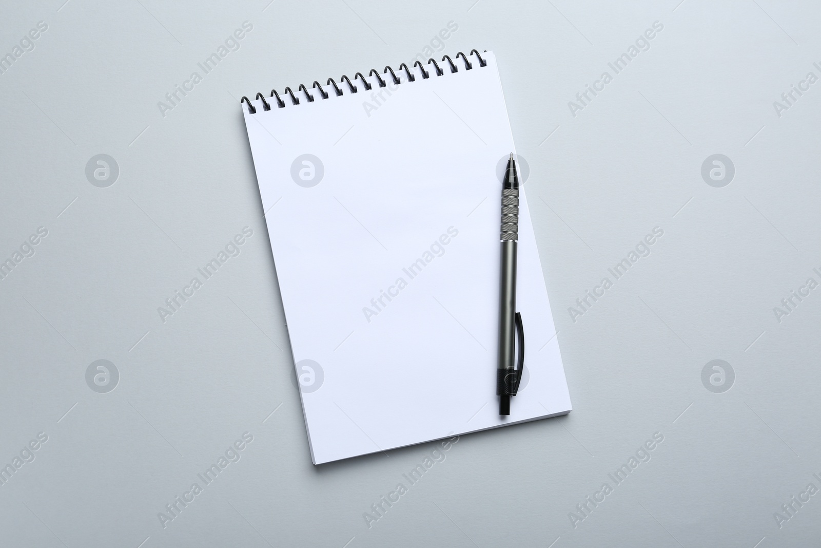 Photo of One notebook and pen on light grey background, top view. Space for text