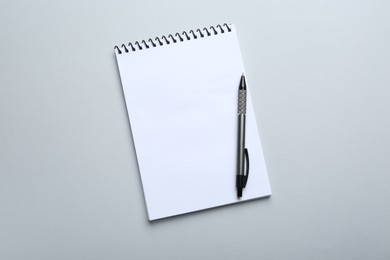 One notebook and pen on light grey background, top view. Space for text