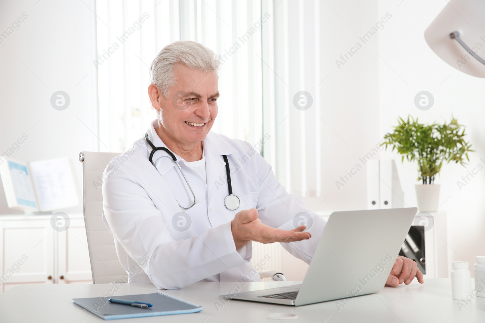 Photo of Doctor consulting patient using video chat on laptop in clinic