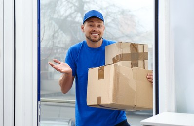 Photo of Emotional courier with damaged cardboard boxes in doorway. Poor quality delivery service
