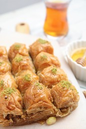 Photo of Delicious sweet baklava with pistachios on parchment paper, closeup