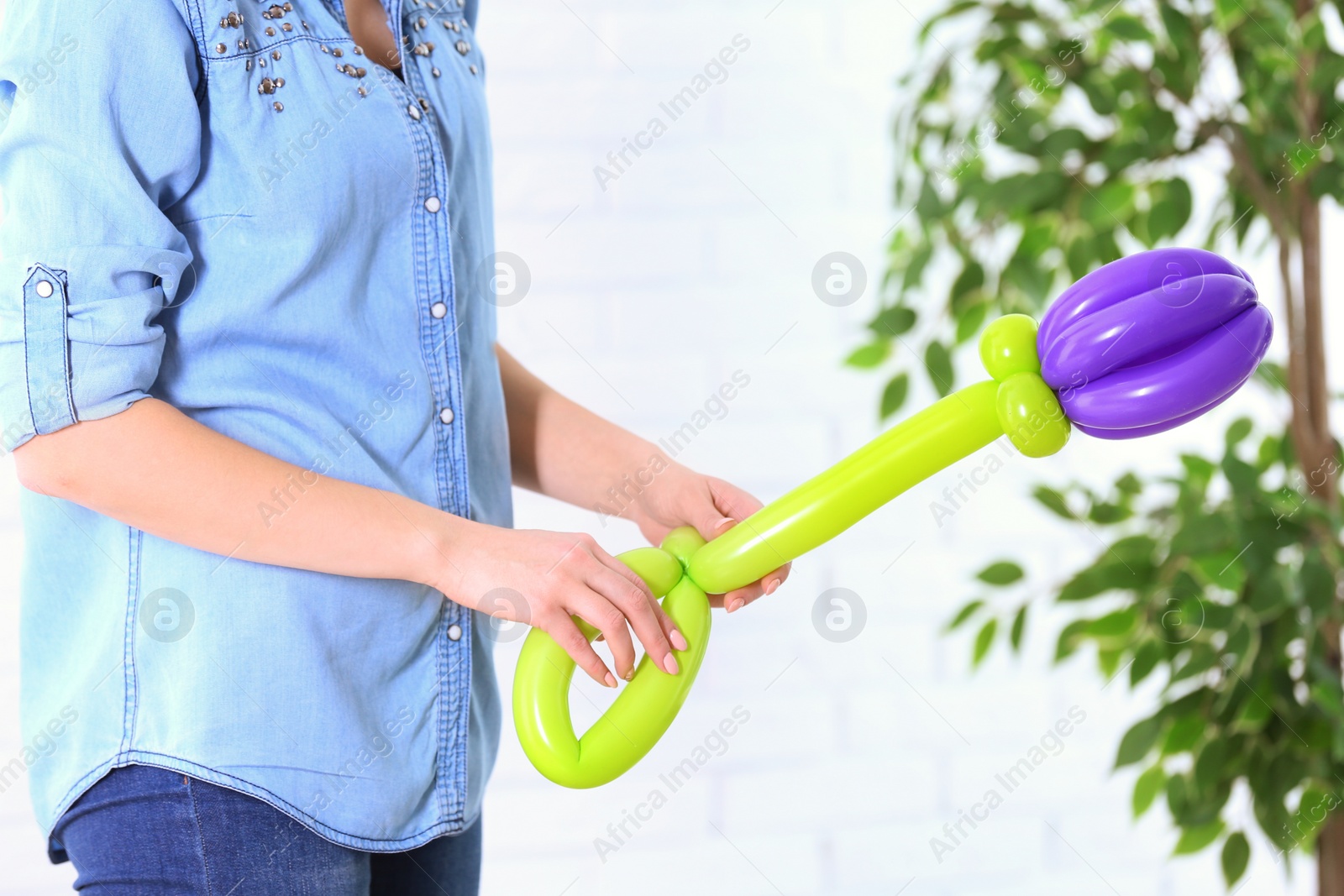 Photo of Woman making balloon figure on blurred background, closeup