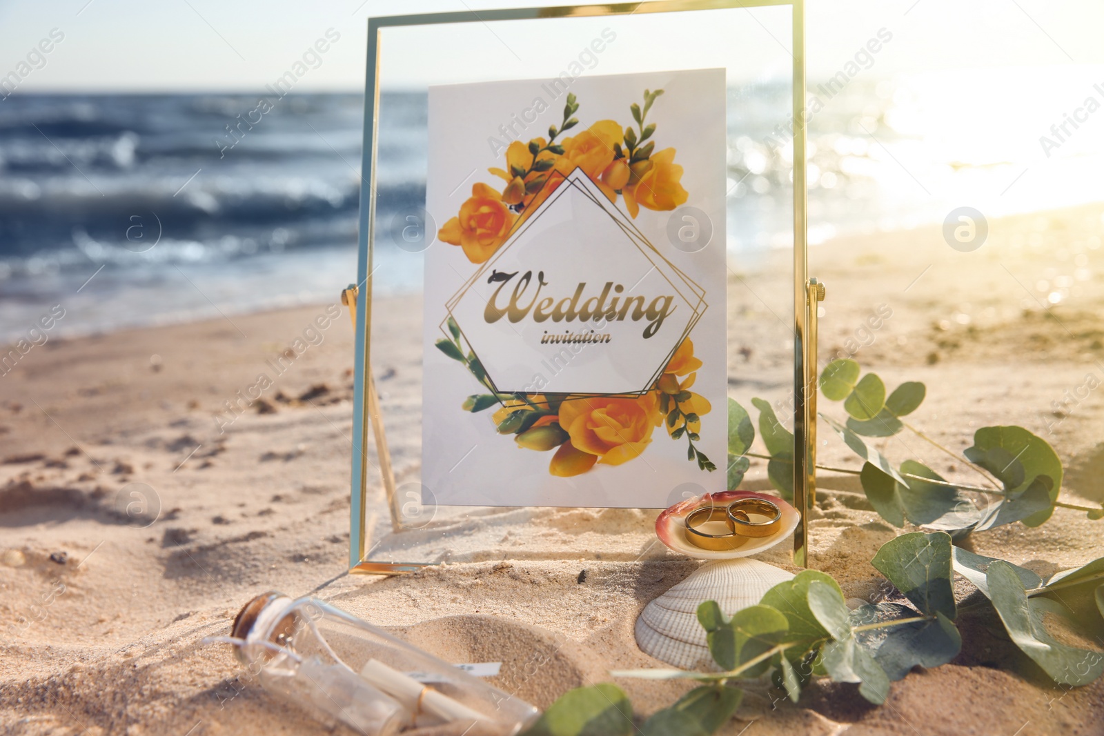 Photo of Composition with gold wedding rings on sandy beach