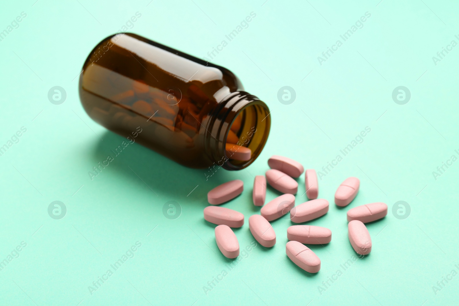 Photo of Vitamin pills and bottle on mint color background, closeup