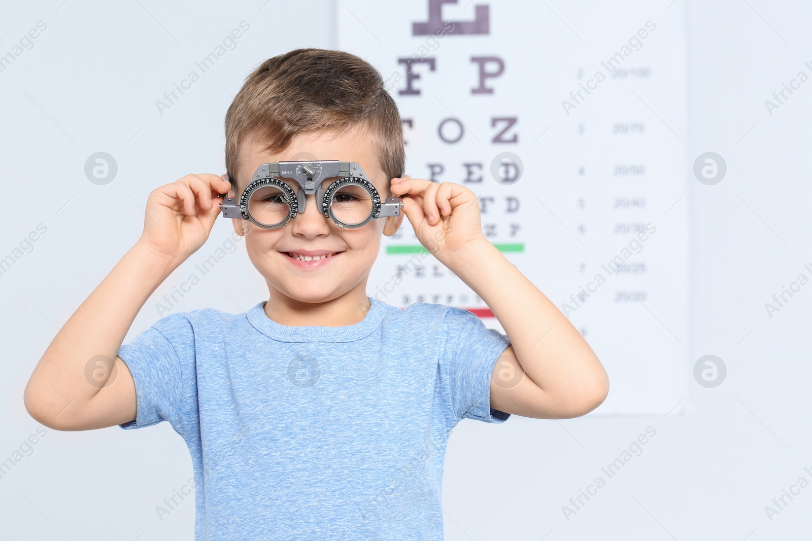 Photo of Little boy with trial frame near eye chart in hospital, space for text. Visiting children's doctor