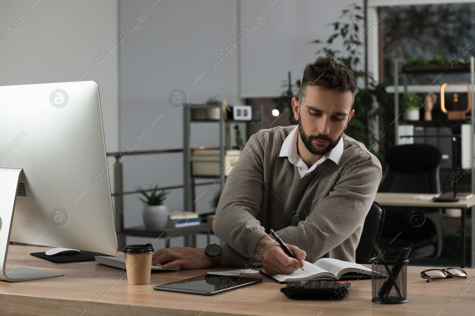 Photo of Man with notebook working at table in office