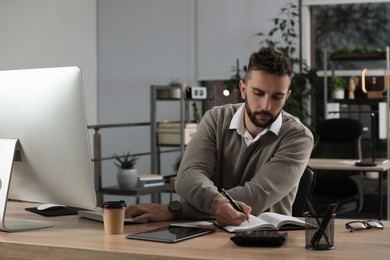 Man with notebook working at table in office