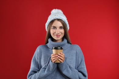 Photo of Happy beautiful woman with paper cup of mulled wine on red background