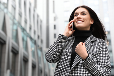 Photo of Beautiful woman in stylish suit talking on phone outdoors. Space for text