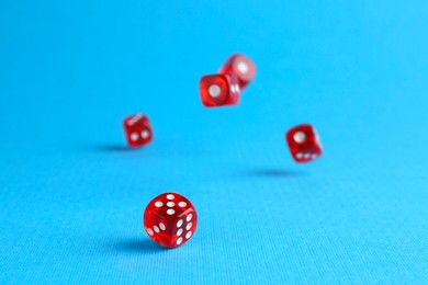 Many red game dices falling on light blue background