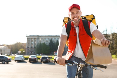 Photo of Male courier on bicycle delivering food in city