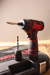 Electric screwdriver, drill chuck and case on wooden table
