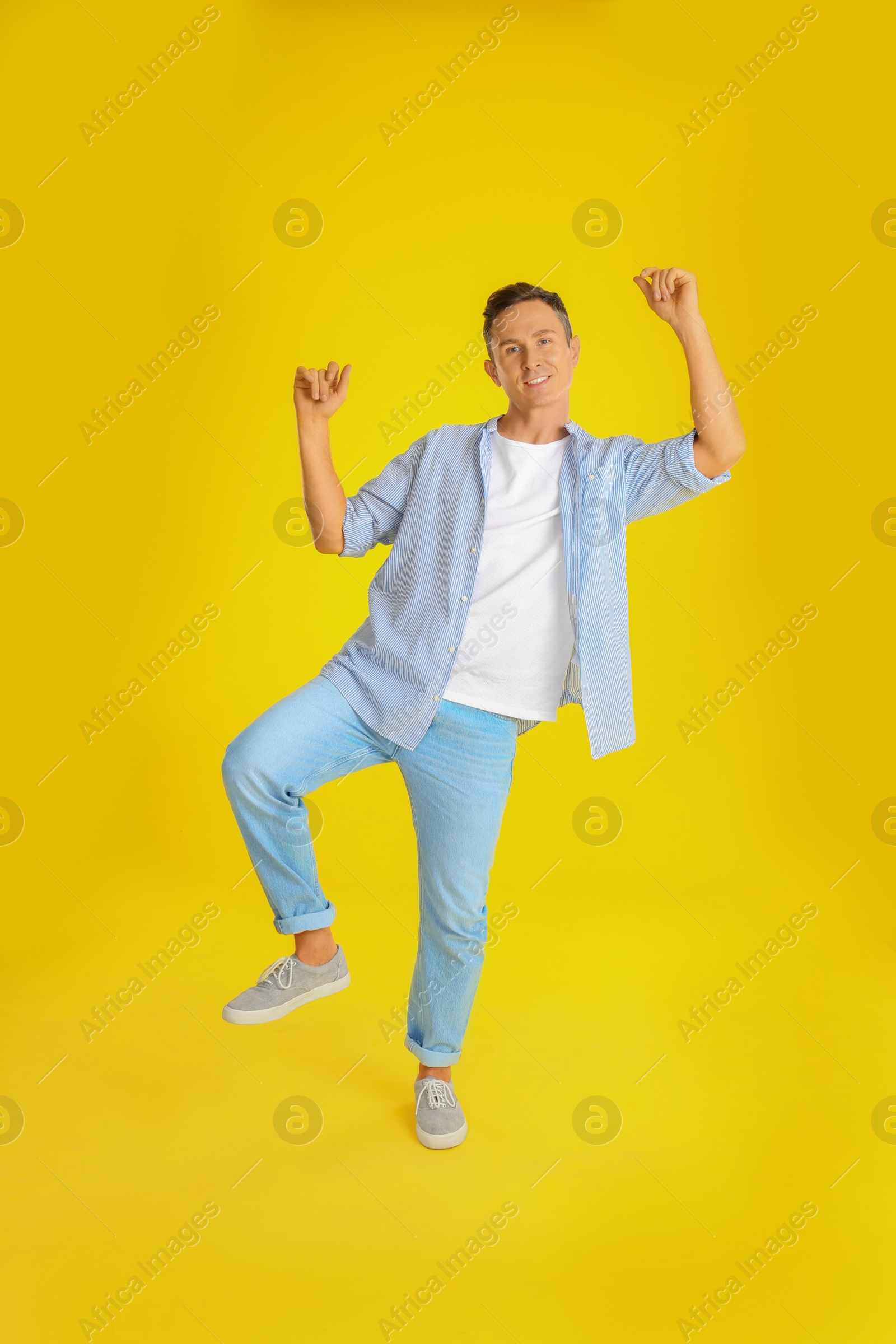 Photo of Happy attractive man dancing on yellow background