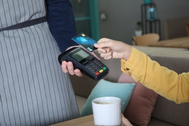 Photo of Client using credit card machine for non cash payment in cafe, closeup