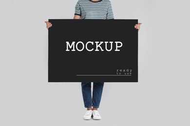 Image of Woman holding black poster with text Mockup Ready To Use on light background, closeup