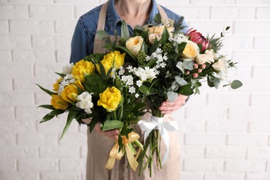 Photo of Woman with beautiful bouquets near white brick wall, closeup