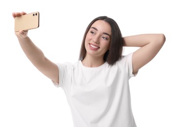 Smiling young woman taking selfie with smartphone on white background