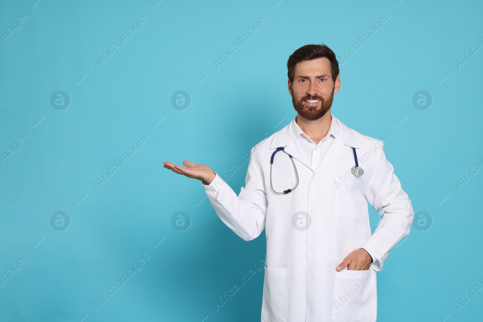 Photo of Happy doctor with stethoscope on light blue background. Space for text