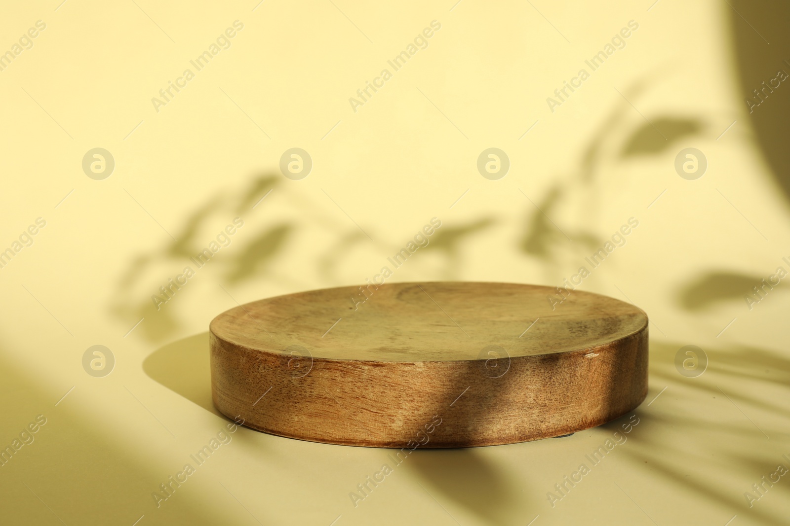 Photo of Presentation of product. Wooden podium on yellow background. Space for text