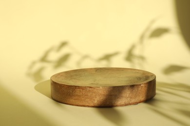 Photo of Presentation of product. Wooden podium on yellow background. Space for text