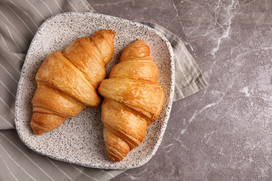 Photo of Tasty fresh croissants on brown marble table, flat lay. Space for text