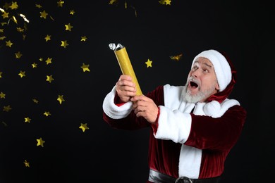 Photo of Emotional man in Santa Claus costume blowing up party popper on black background