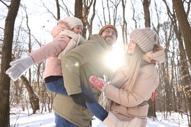 Happy family spending time together in sunny snowy forest