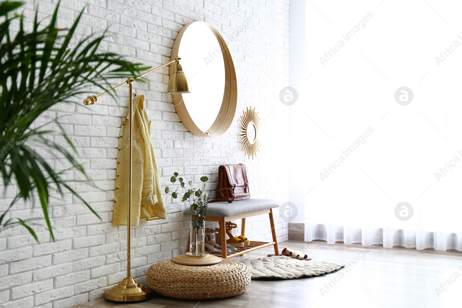 Photo of Hallway interior with big round mirror and shoe storage bench near brick wall. Space for text